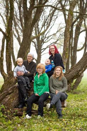 Ryhmäkuva Arjen Avuxi -yrityksen työntekijöistä, jotka istuvat kyljelleen kallistuneen puun rungolla